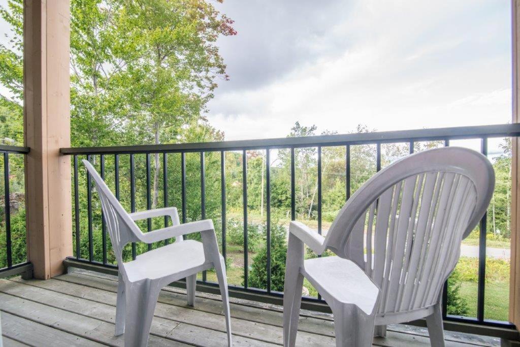 two chairs sitting on a porch with a railing at Auberge du Lac Morency in Saint-Hippolyte