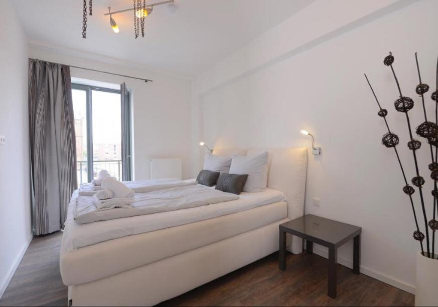 a white bedroom with a white couch and a window at Appartment Ferienwohnung mit großer Terrasse Ohlerich Speicher Wismar in Wismar