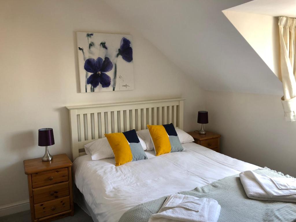 a bedroom with a bed with yellow and white pillows at Jubilee House in Oakham