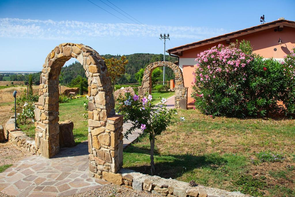 a stone archway in a yard with a house at Poggio Mariett in Castiglione della Pescaia