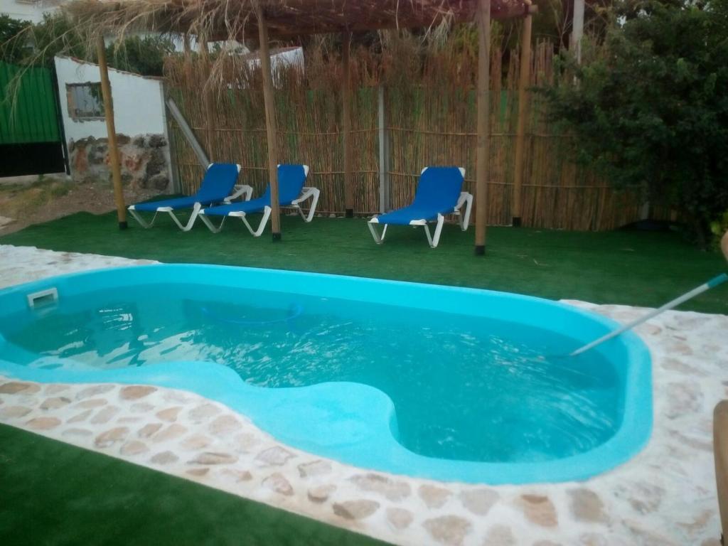 una piscina in un cortile con sedie e tavolo di Alojamiento rural El Batán a Priego de Córdoba