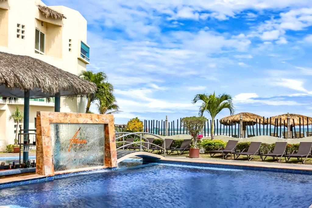 a pool at a resort with chairs and umbrellas at Artisan Family Hotels and Resort Collection Playa Esmeralda in Chachalacas