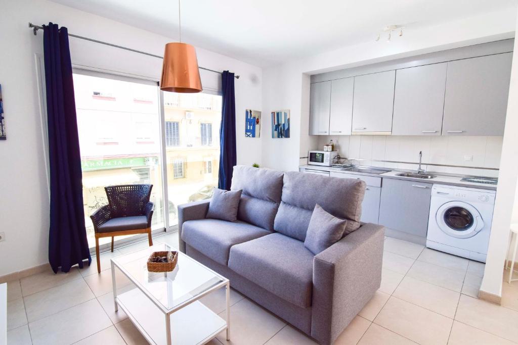sala de estar con sofá y cocina en Malaga City Suites Barceló 30, en Málaga