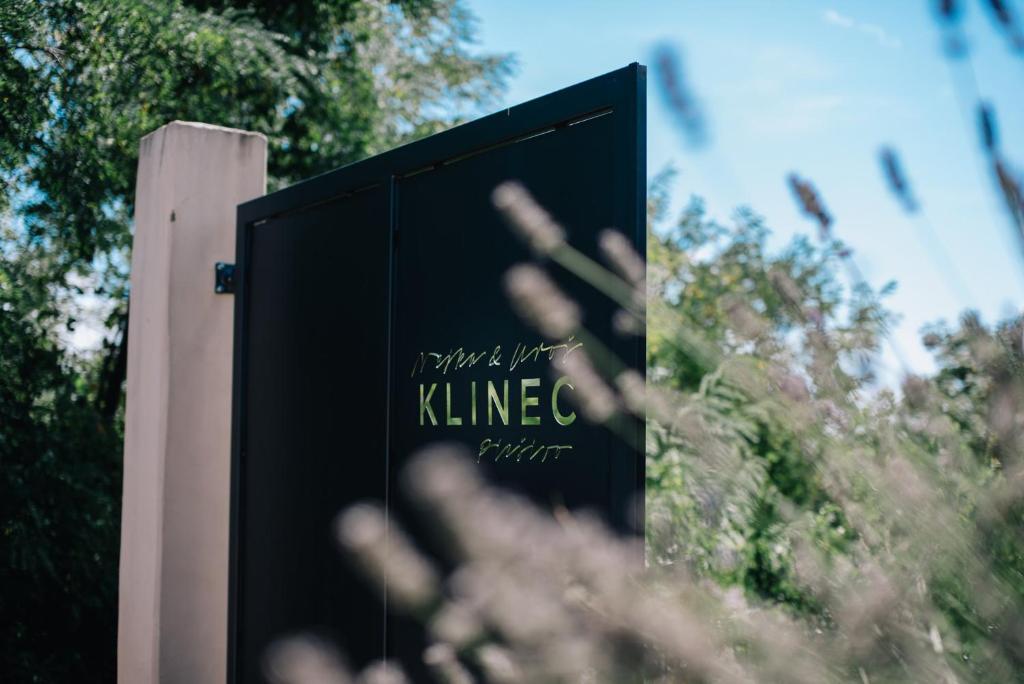 a sign in front of a building with trees at Klinec Plešivo Art Rooms in Dobrovo