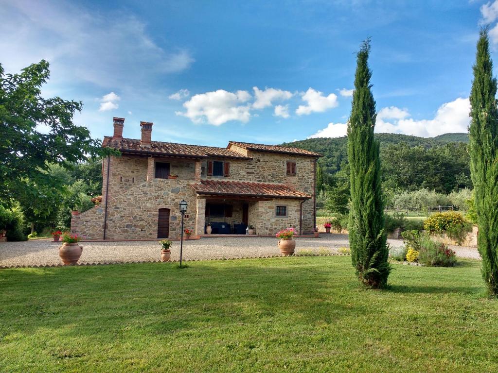 une grande maison en pierre avec des arbres dans une cour dans l'établissement Casale I Burroni, à Arezzo
