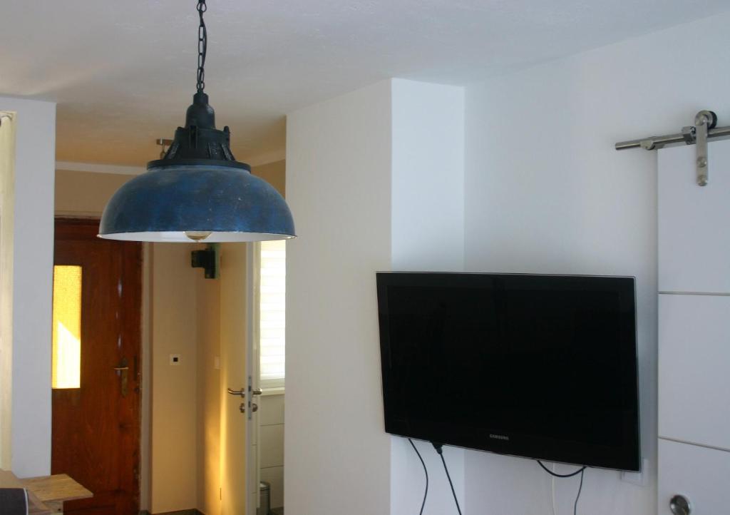 een televisie en een hanglamp in een kamer bij Ferienwohnung Am See 55 in Bad Saarow