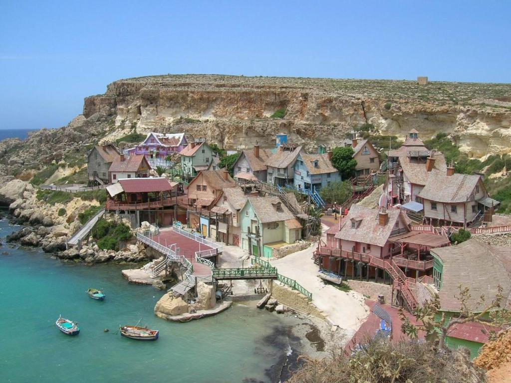 a village on a hill with boats in the water at Modern 2BR Sliema Apartment in Sliema