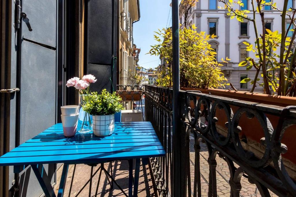 a blue table on a balcony with flowers on it at JOIVY Charming Apt with Terrace in the very heart of Milan in Milan