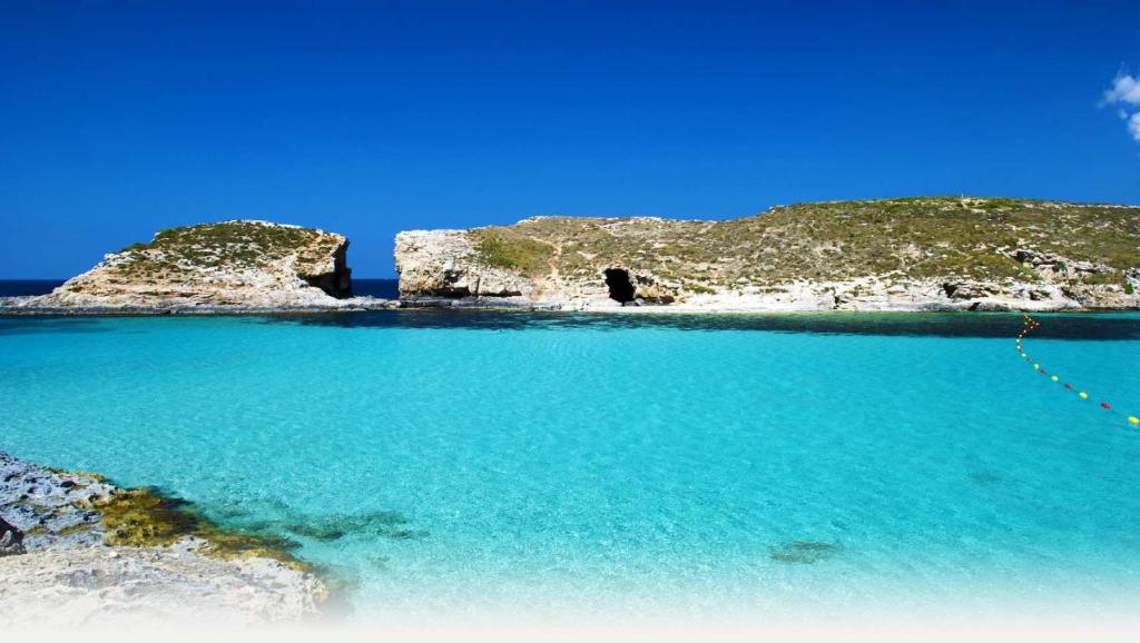 a view of a beach with blue water and rocks at Modern 2BR Sliema Apartment in Sliema