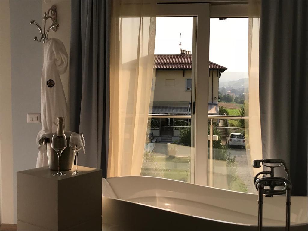 een badkamer met een bad en een groot raam bij Maison Petit Perlage B&B and Champagne in Serralunga di Crea