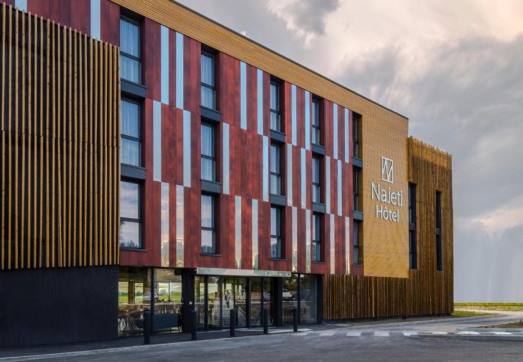 um grande edifício com uma placa no lado em Najeti Hôtel Lille Nord em Bondues