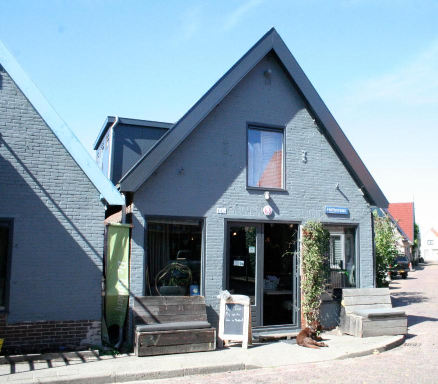 a building with a dog sitting in front of it at Het Huis van de Wadden in Den Oever