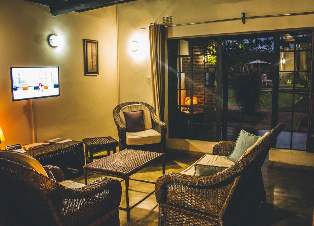 Eden Estates and Lodge في ليلونغوي: غرفة معيشة مع كراسي الخوص وتلفزيون