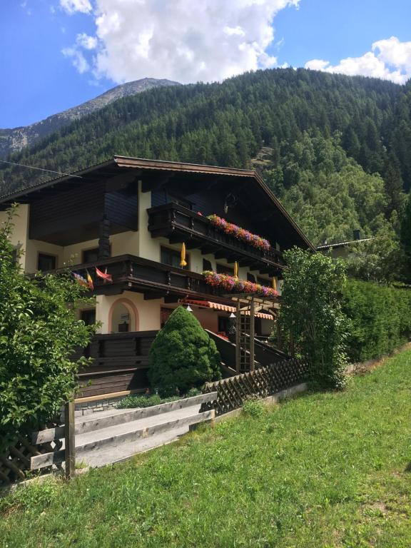 ein Haus auf einem Hügel mit Bergen im Hintergrund in der Unterkunft Tirolerheim Grüner in Sölden