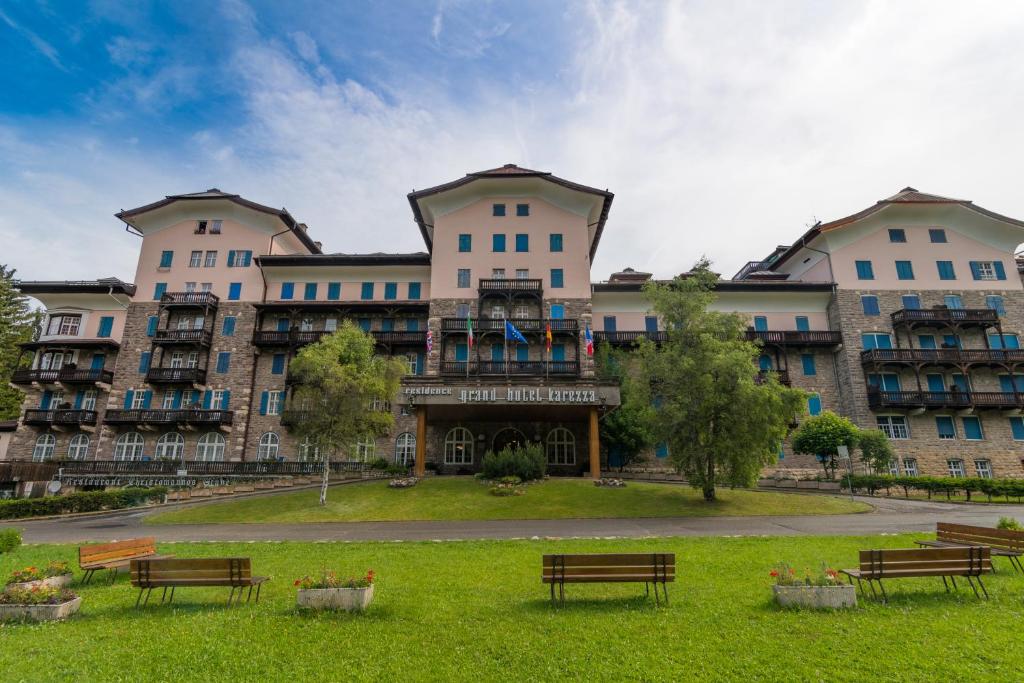 un grand immeuble avec bancs dans un parc dans l'établissement Residence Grand Hotel Carezza, à Nova Levante