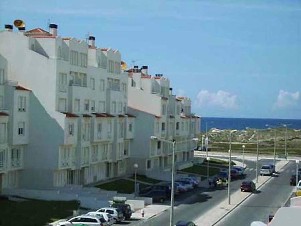 un gran edificio con coches estacionados en un estacionamiento en Beach and Surf en Peniche