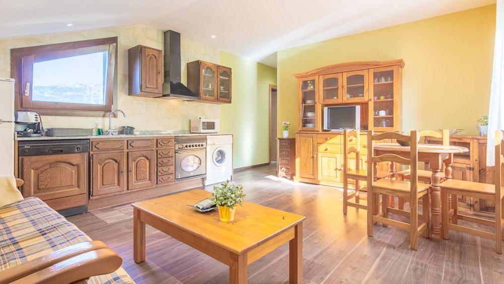 cocina con armarios de madera, mesa y comedor en Apartamento Llorens, en Arasán