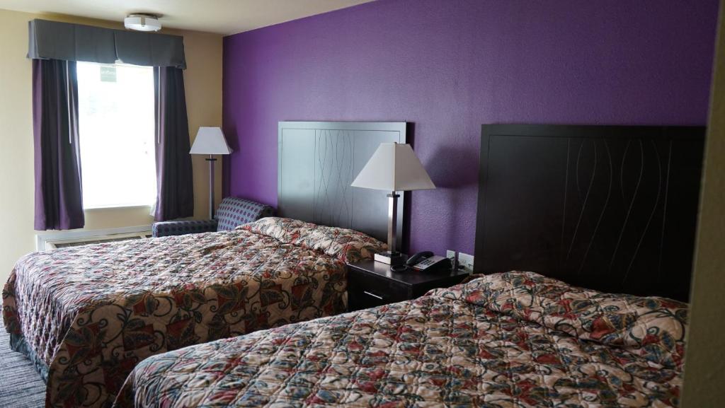 Cette chambre d'hôtel comprend 2 lits et des murs violets. dans l'établissement Village Motor Inn, à Austin