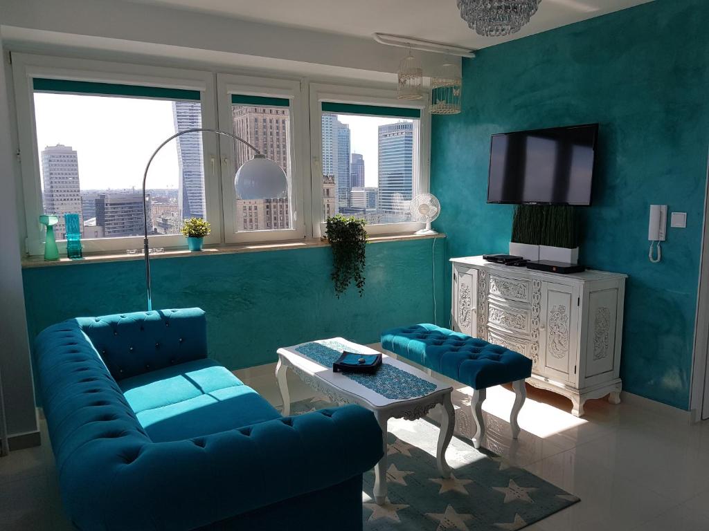 uma sala de estar com um sofá azul e uma mesa em Centre Apartamenty Warszawa em Varsóvia