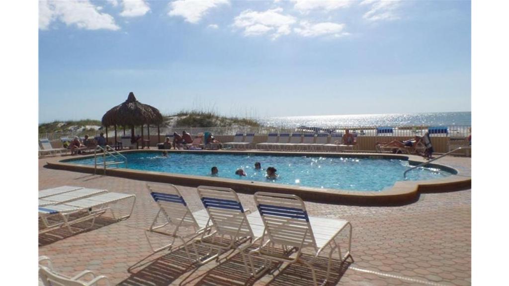 a pool with chairs and people in the water at Holiday Villas III #311 in Clearwater Beach