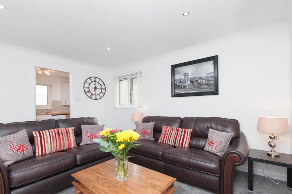 a living room with a brown leather couch and a table at Prime Commuter Executive Apartment Dunfermline in Dunfermline