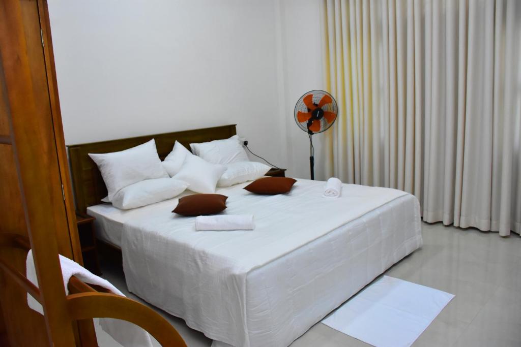 1 dormitorio con 1 cama con sábanas blancas y ventilador en Ella, Nine Arch Holiday Resort en Ella