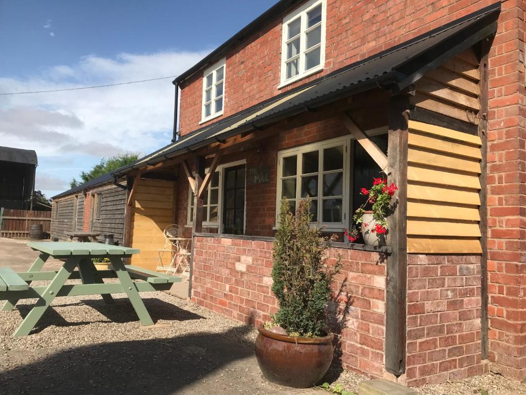 a picnic table in front of a brick building at The Mill at Rose Villa Farm in Hereford