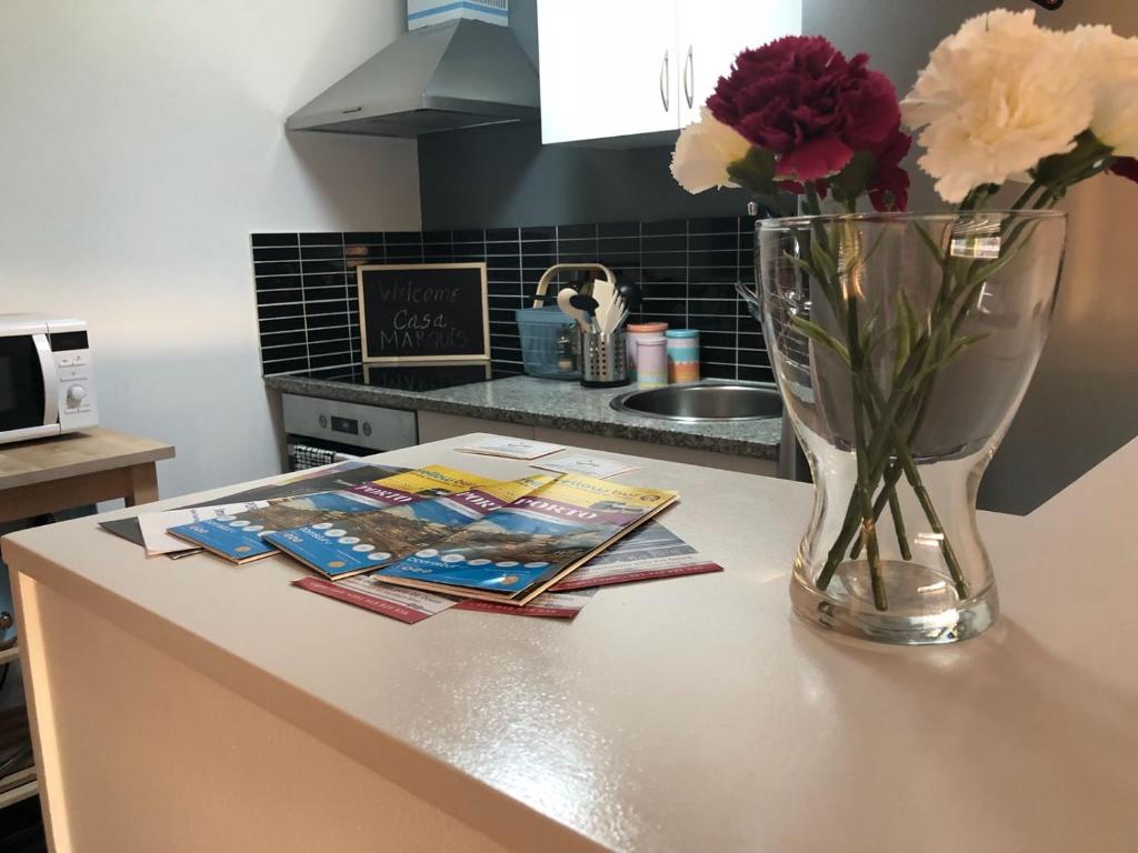 un mostrador de cocina con un jarrón de flores y revistas en Casa Marquês, en Oporto