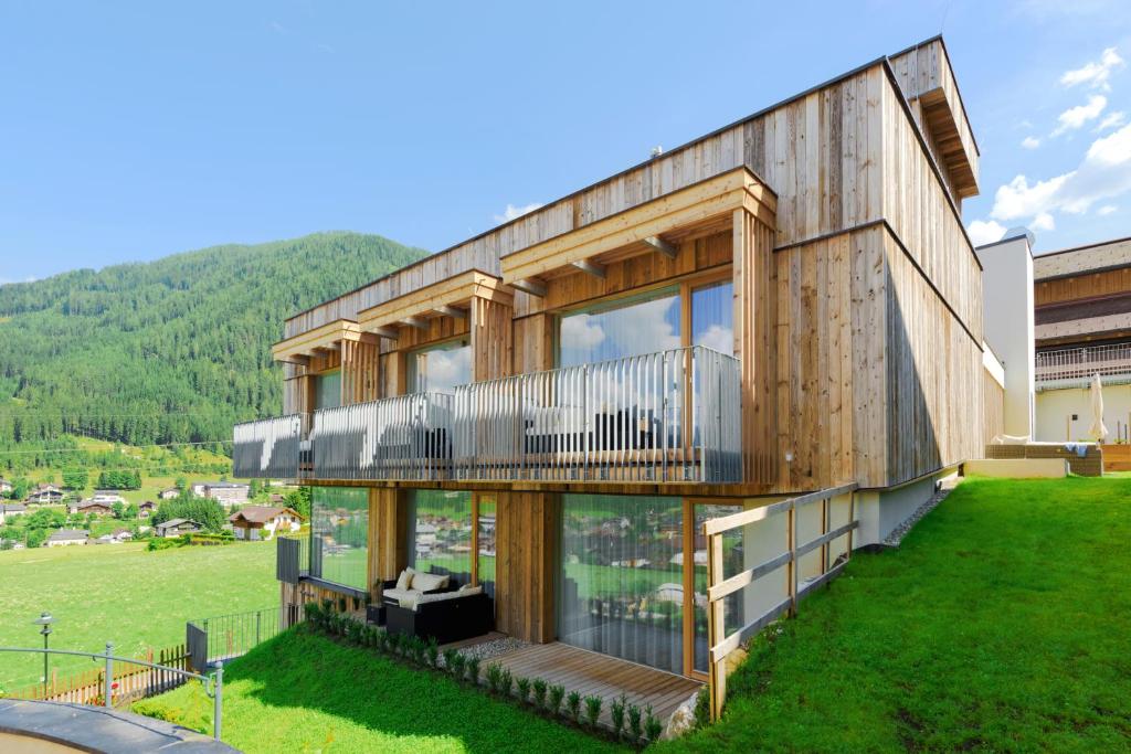 ein Holzhaus mit einem Balkon auf einem grünen Feld in der Unterkunft Appartements Luna in Flachau