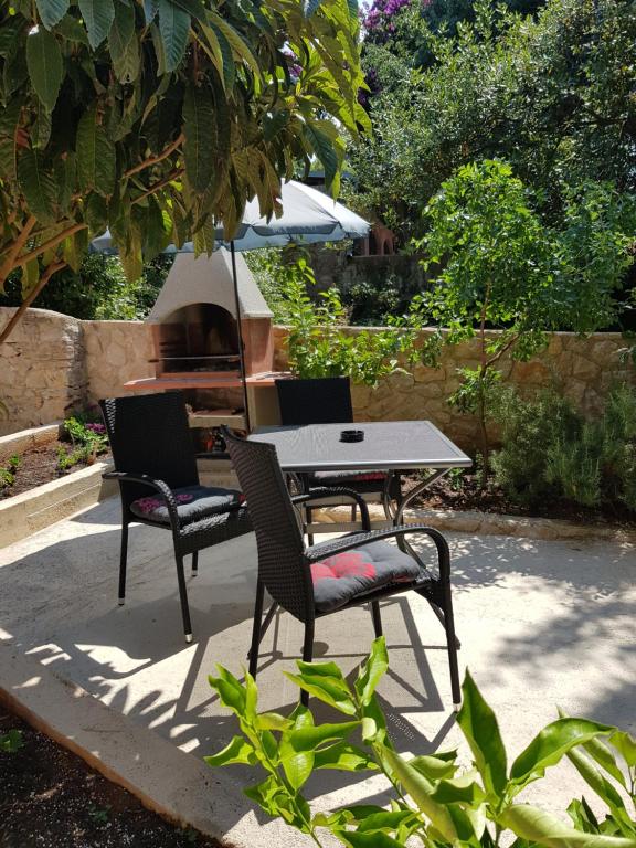 a table and chairs and an umbrella in a garden at Apartment Zdenka in Veli Lošinj