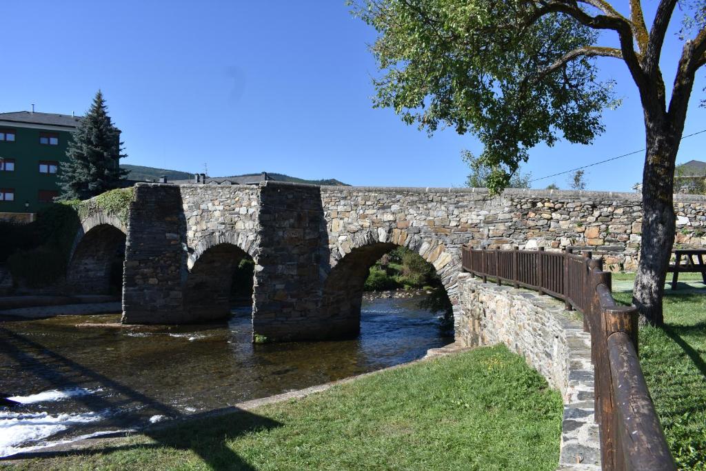 un puente de piedra con dos arcos sobre un río en Apartamentos Picea Azul, en Vega de Espinareda