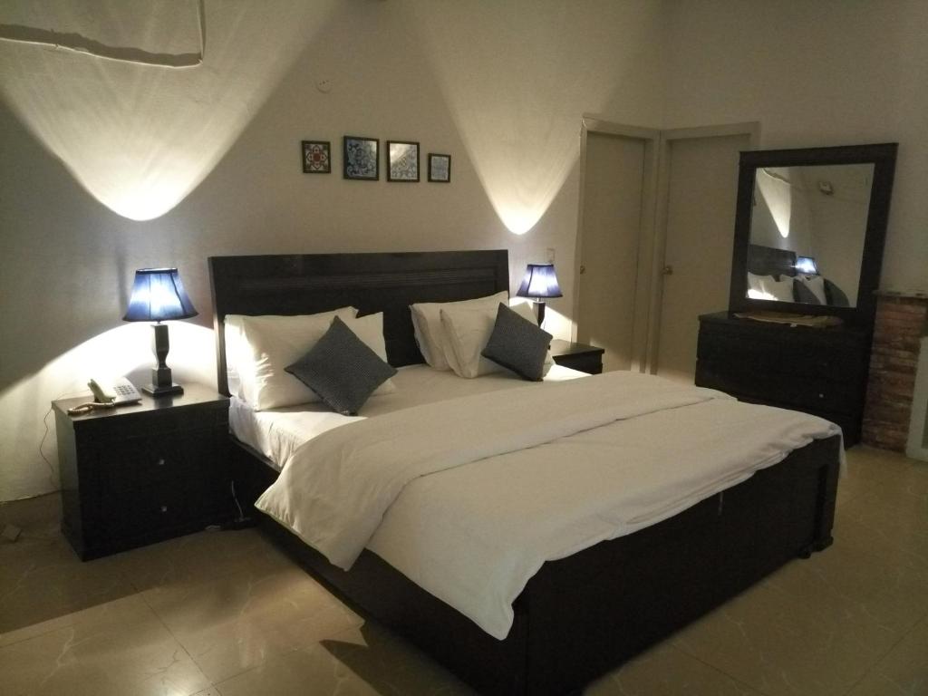 a bedroom with a large bed with two lamps at Pyramid International Guest House in Islamabad