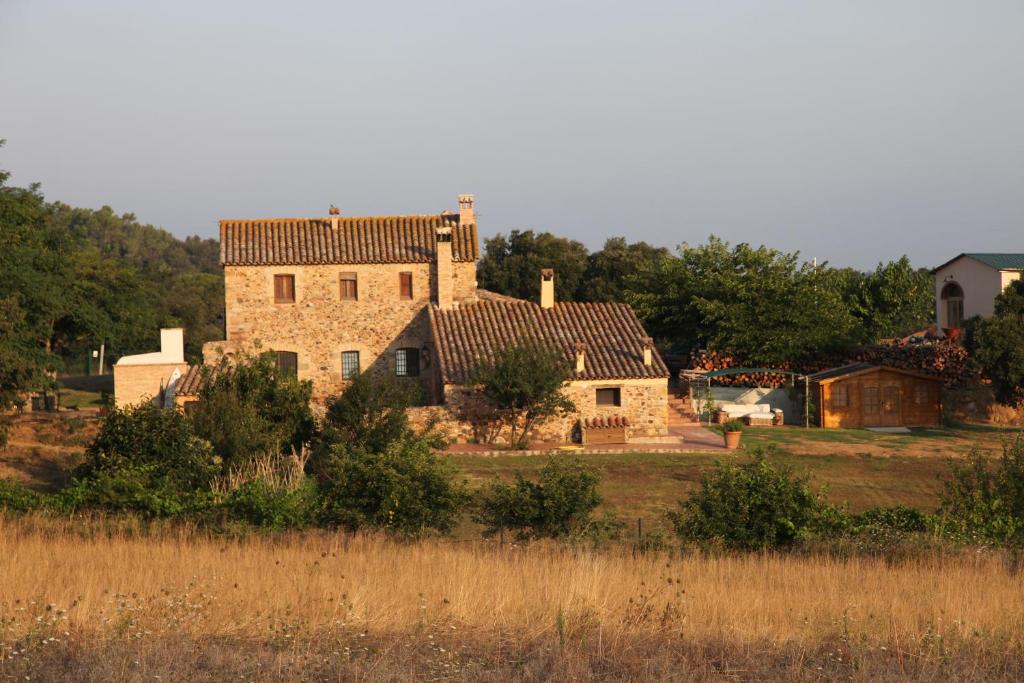 ein altes Steinhaus auf einem Feld mit Bäumen in der Unterkunft Can Cabanyes in Llagostera