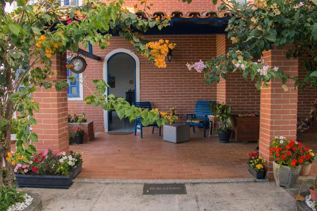 um edifício de tijolos com um pátio com flores e plantas em Hostel Villa Virtudes em Guarapari