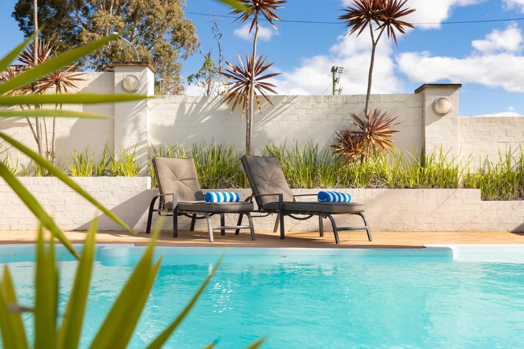 two chairs sitting next to a swimming pool at Sunseeker Motor Inn in Batemans Bay