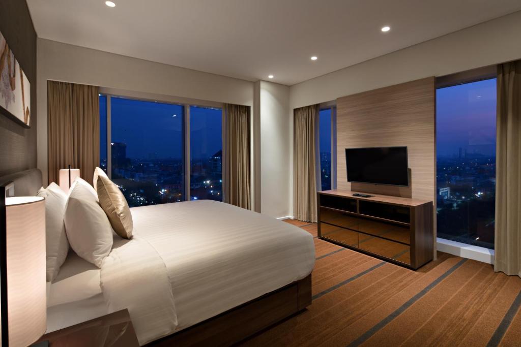 a bedroom with a large bed and a television at Oakwood Hotel & Residence Surabaya in Surabaya