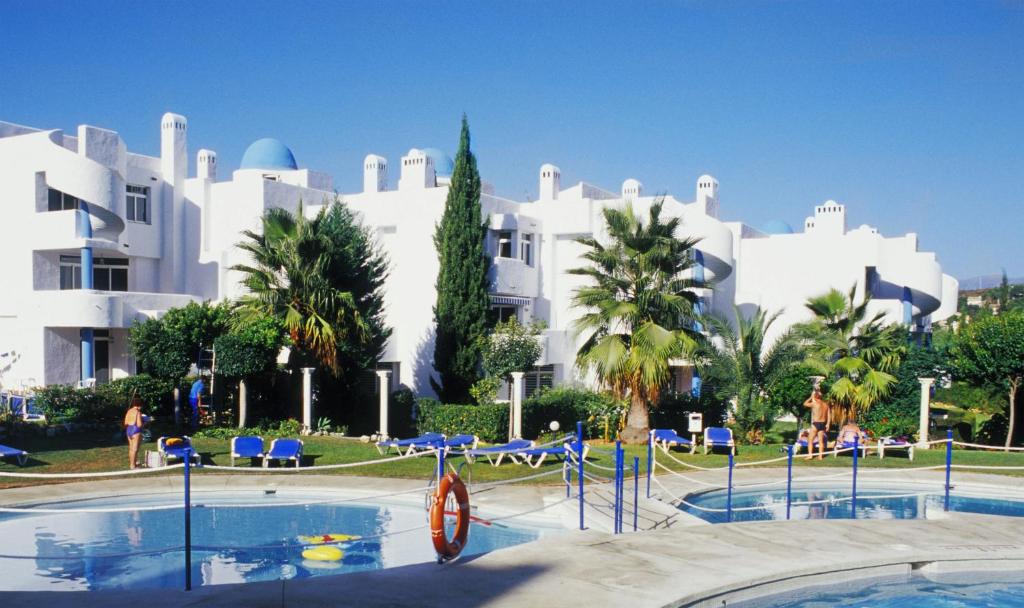 a large white building with palm trees and a swimming pool at Ona Campanario in La Cala de Mijas