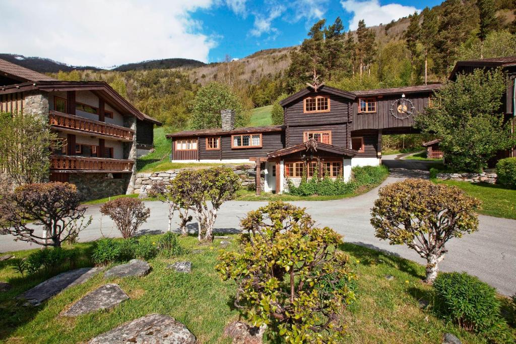 a large house with a driveway in front of a mountain at Elveseter Hotell in Boverdalen