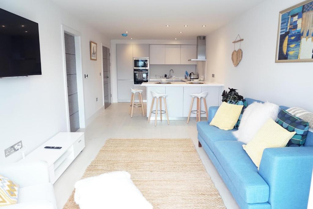 a living room with a blue couch and a kitchen at Saltwater Suites at Fistral in Newquay