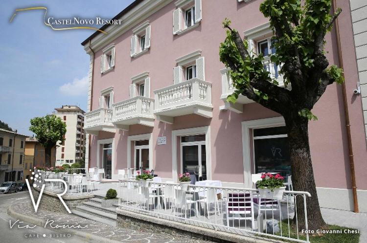 een roze gebouw met witte stoelen ervoor bij Castelnovo Resort in Castelnovo neʼ Monti