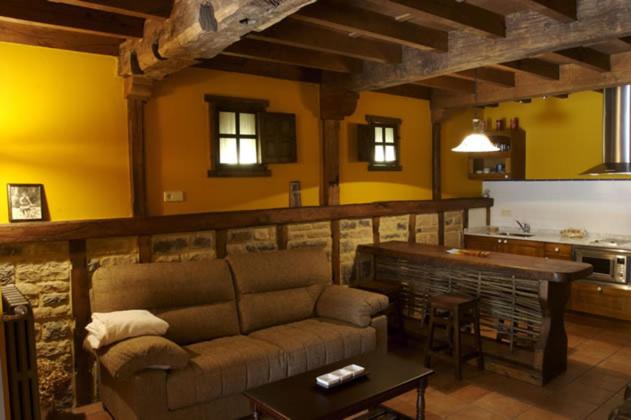 a living room with a couch and a kitchen at La Prida Apartamentos Rurales in Caleao