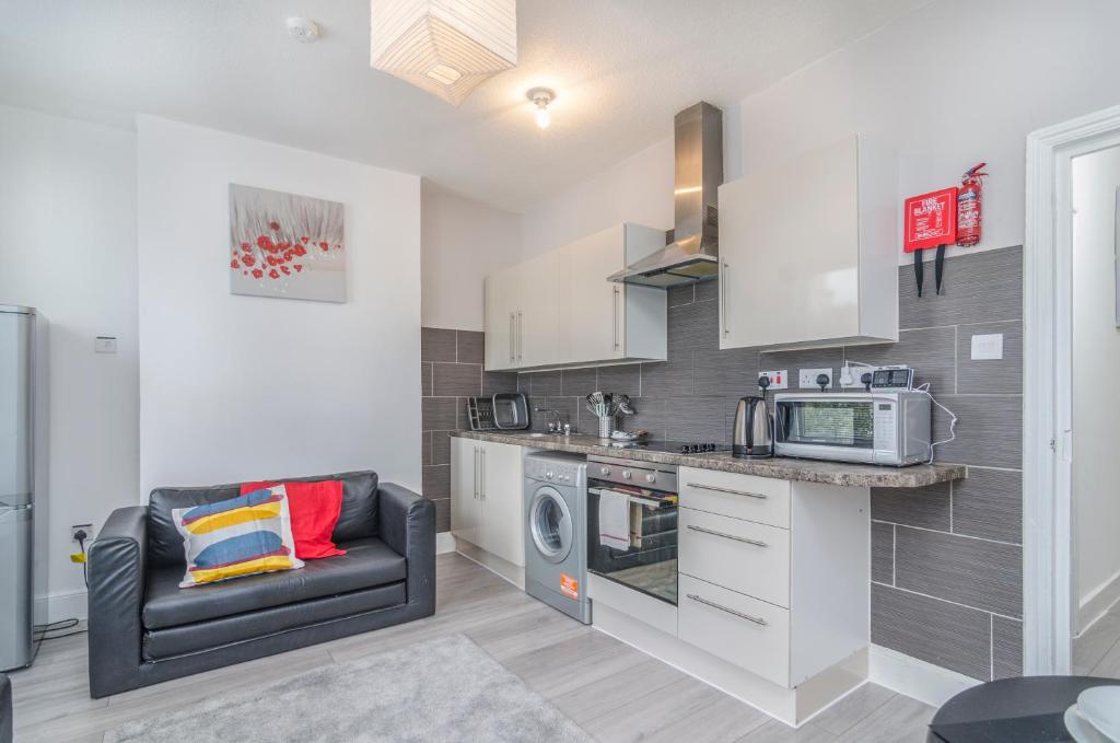 a kitchen with a couch and a microwave at The Rock Apartments in Plumstead