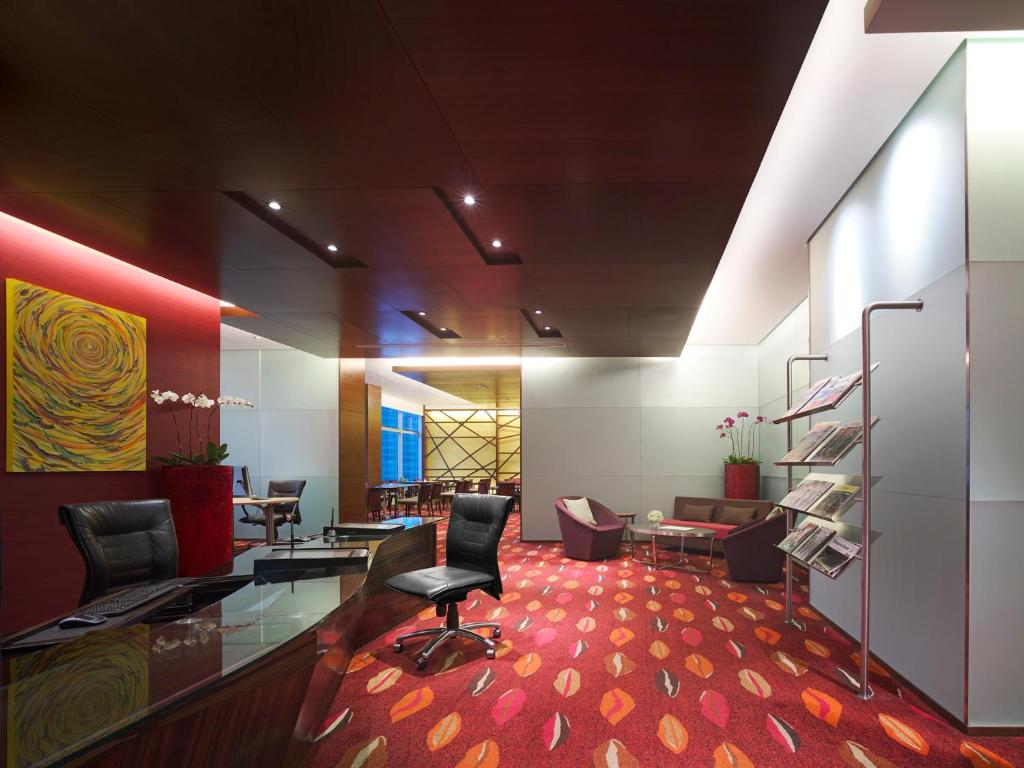 A stylish lobby seating area with leather chairs, glass tables and a vivid patterned carpet.