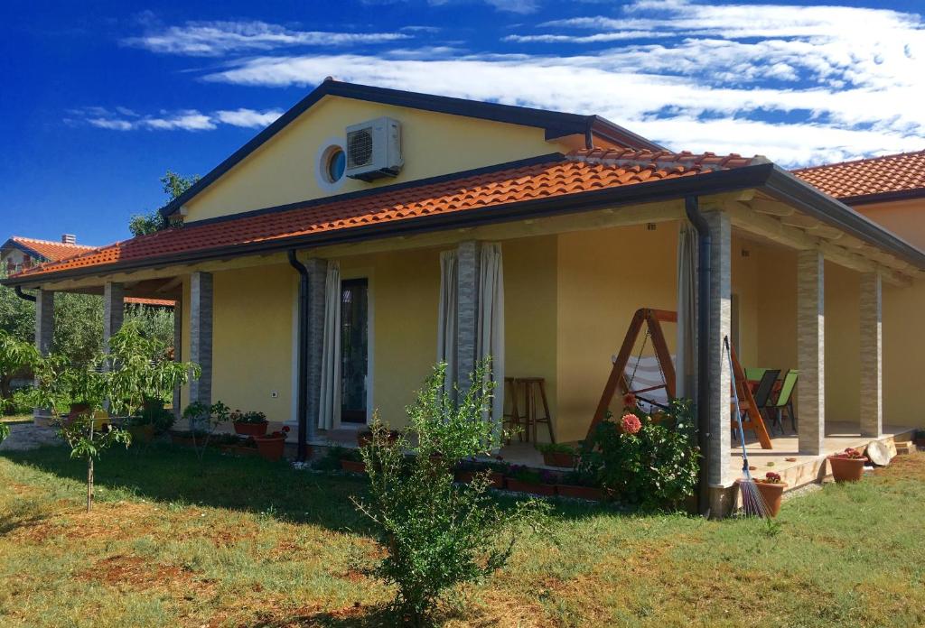 a small yellow house with a roof at Holiday house EMC in Umag