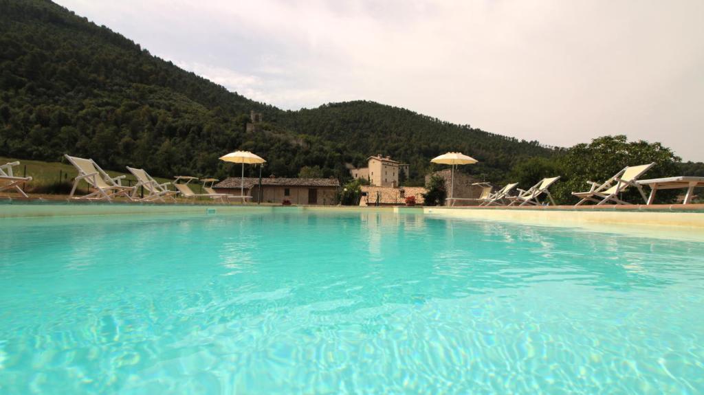 斯波萊托的住宿－伊爾卡薩里諾度假農莊，一个带椅子和遮阳伞的大型蓝色海水游泳池