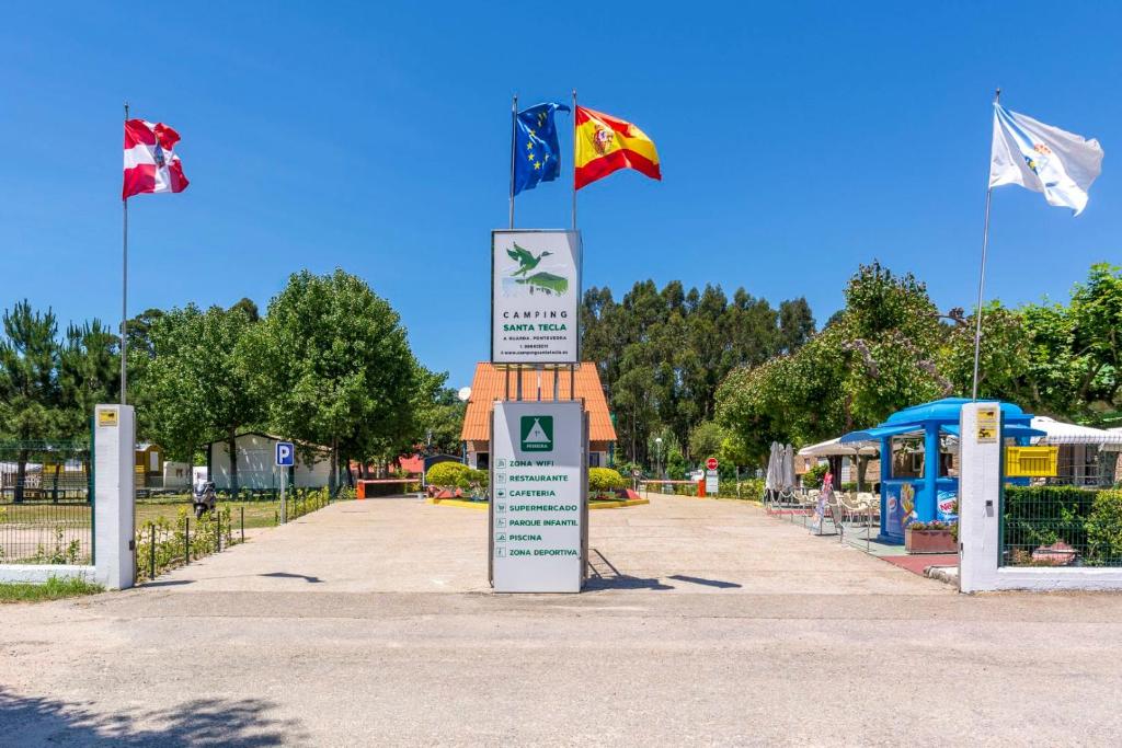 a sign with three flags on top of a street at Camping Santa Tecla in A Guarda