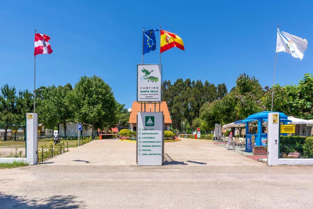 un cartello con tre bandiere in cima a una strada di Camping Santa Tecla ad A Guarda