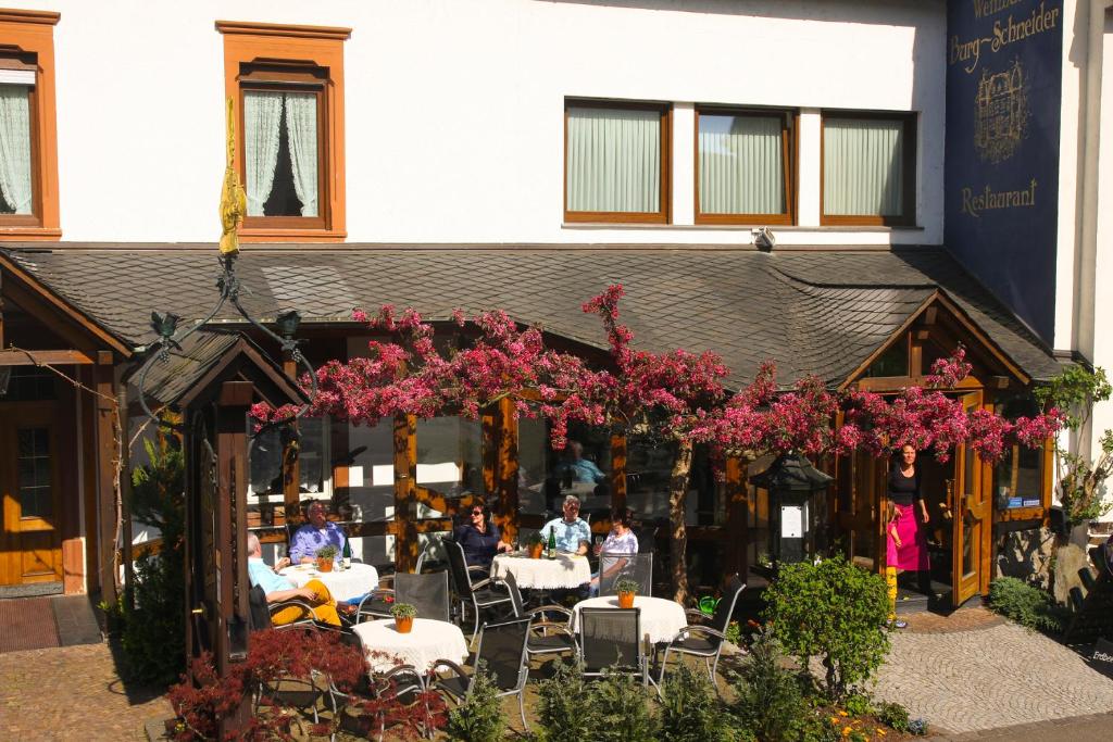 a group of people sitting at tables in front of a building at Weinhaus Burg-Schneider in Reil