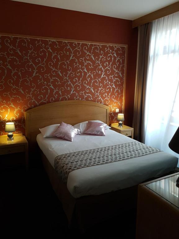 een slaapkamer met een bed met 2 kussens erop bij Hotel Eden in Béthune