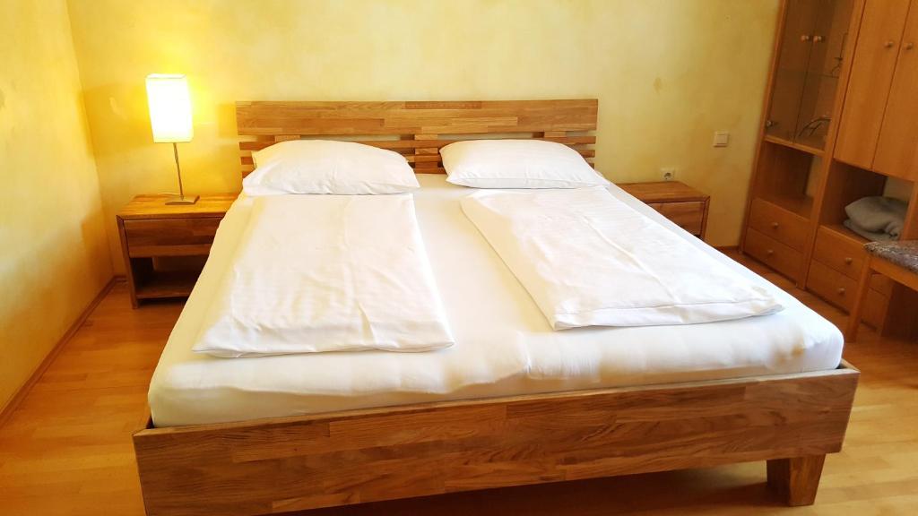1 Schlafzimmer mit 2 Betten mit weißer Bettwäsche und einer Lampe in der Unterkunft Gasthof Paradiesgartl in Kleinpöchlarn